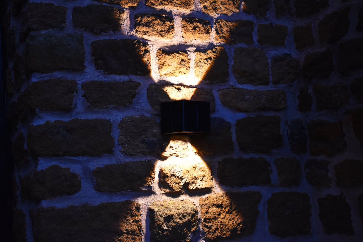 Aptrix solar up and down wall light operating on a stone wall at night