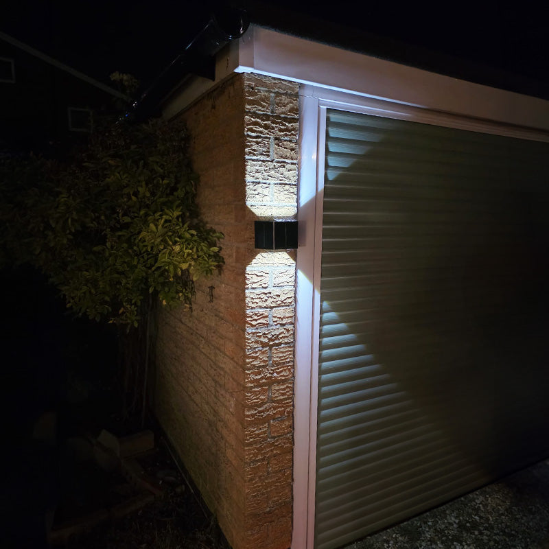 Aptrix solar wall light illuminating a garage entrance